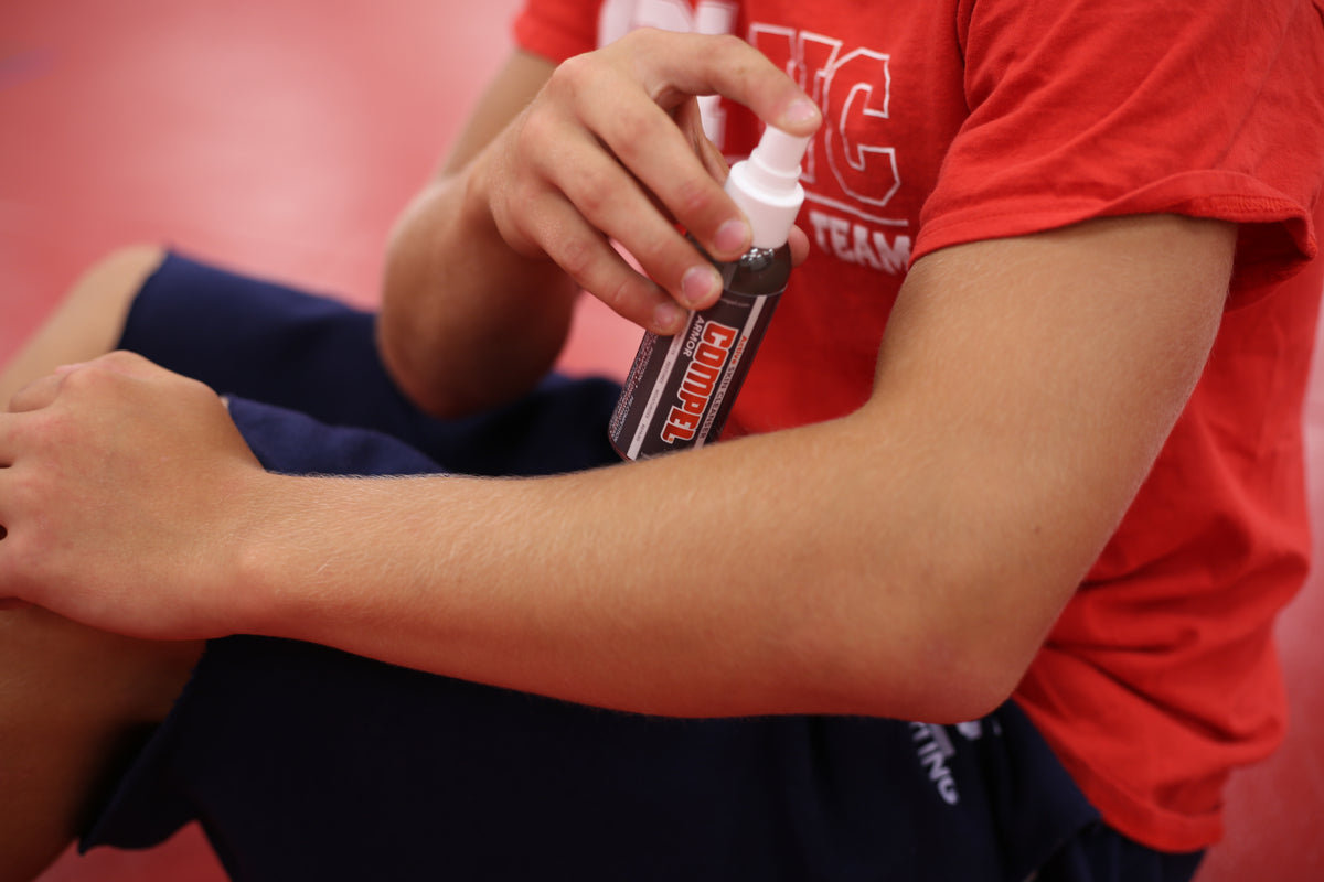 Athlete applying COMPEL ARMOR no-rinse skin cleanser to forearm after training